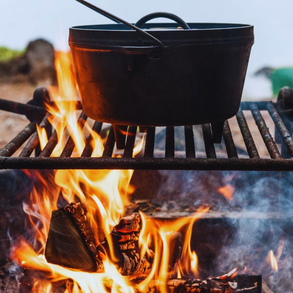 cast iron dutch oven set on a grill grate over a campfire