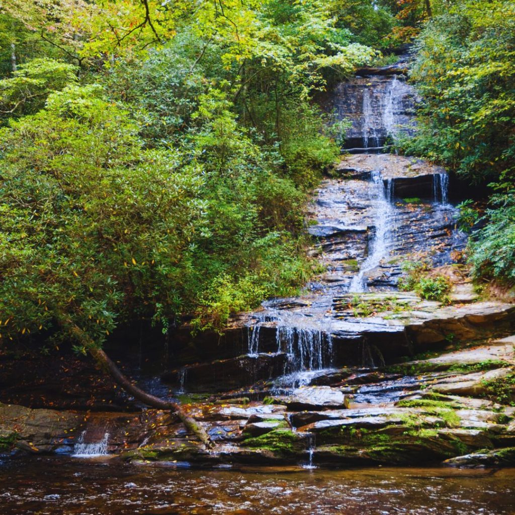 a waterfall on rocks with green trees all around