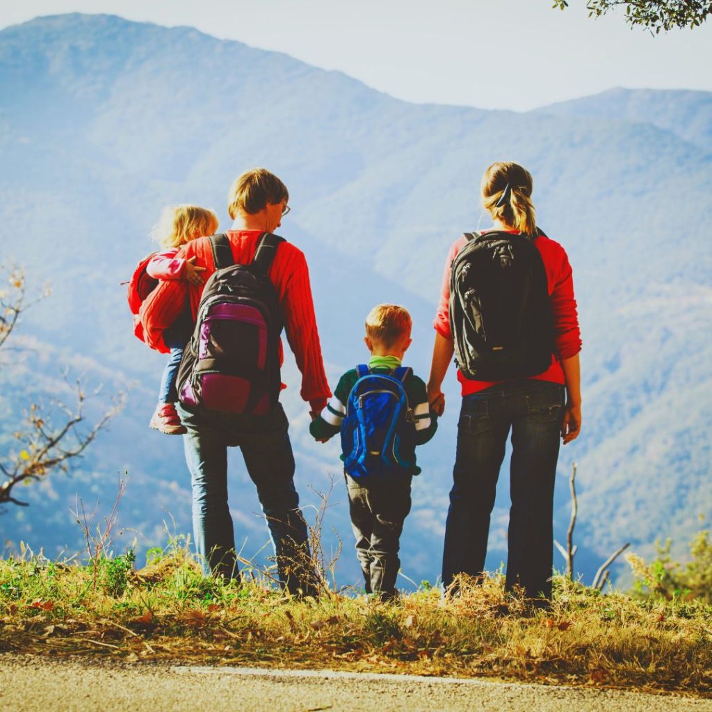 family dressed in red with backpacks looking out across a valley