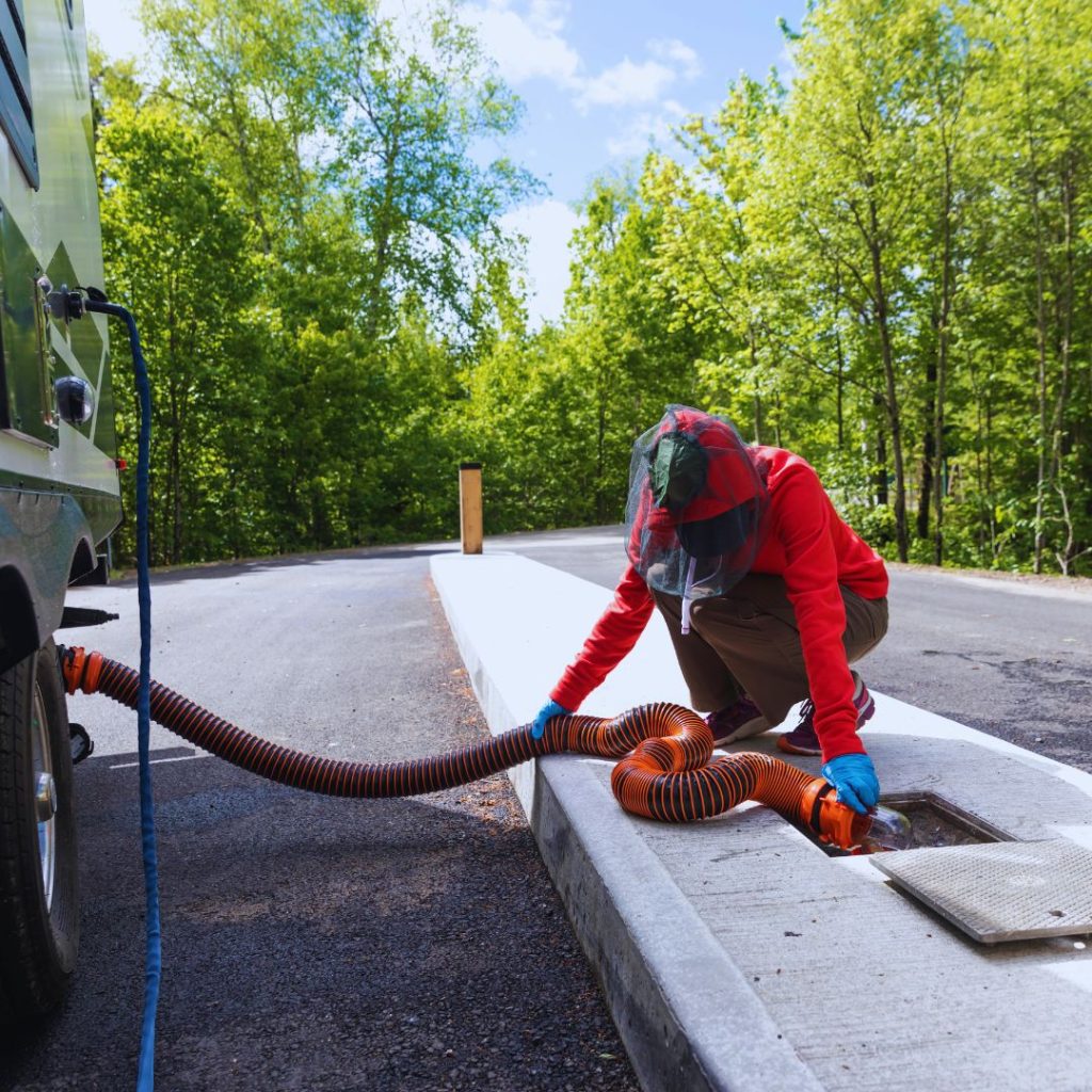 person in red directing an RV sewage hose to the dump site in the ground