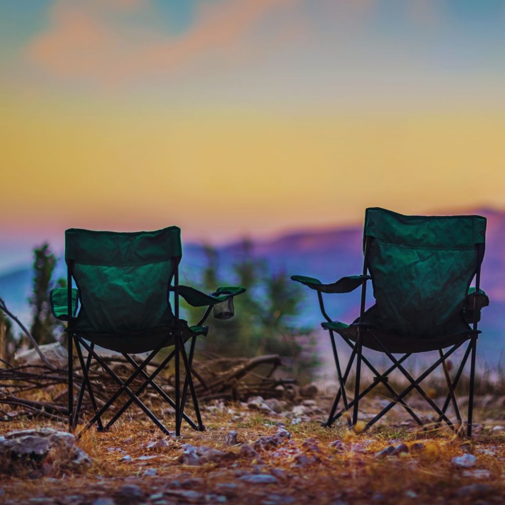 green camp chair set up with mountains in the distance