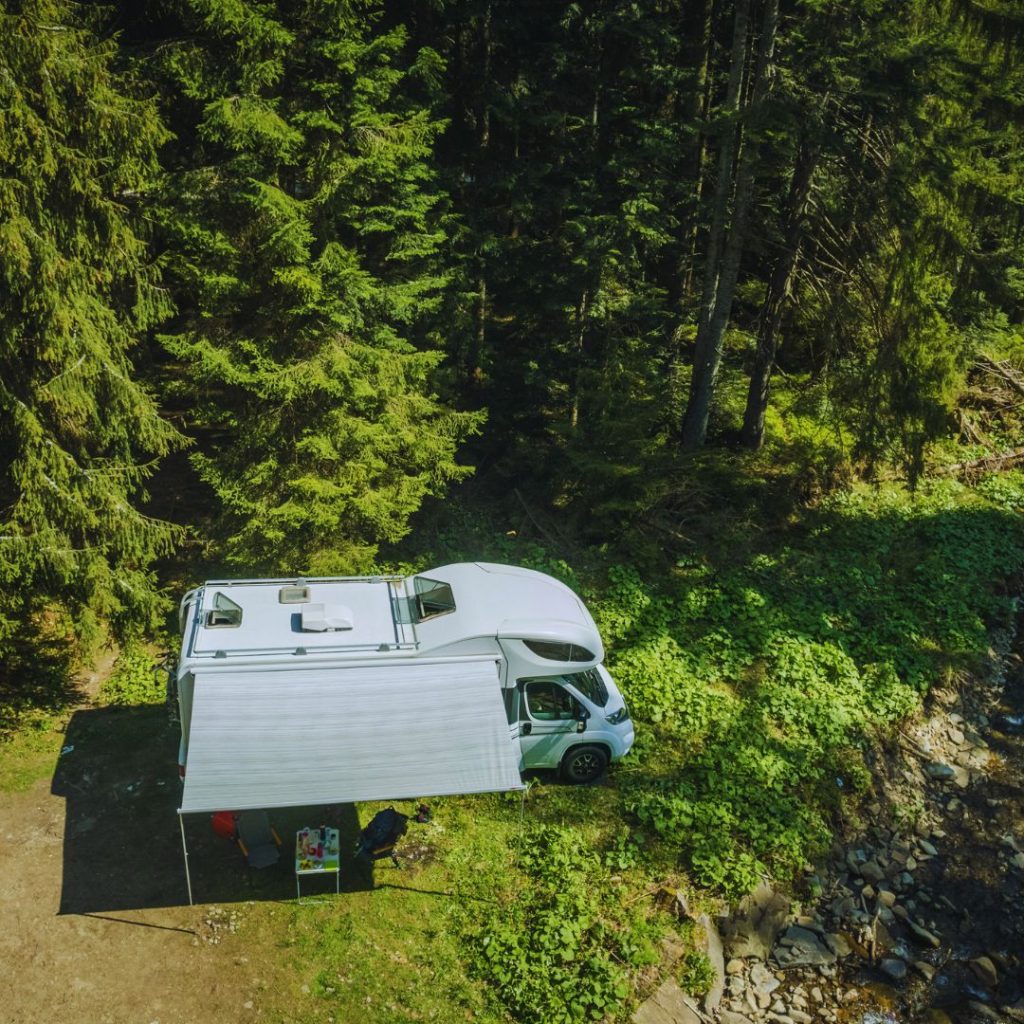 motorhome parked near a river with the awning out