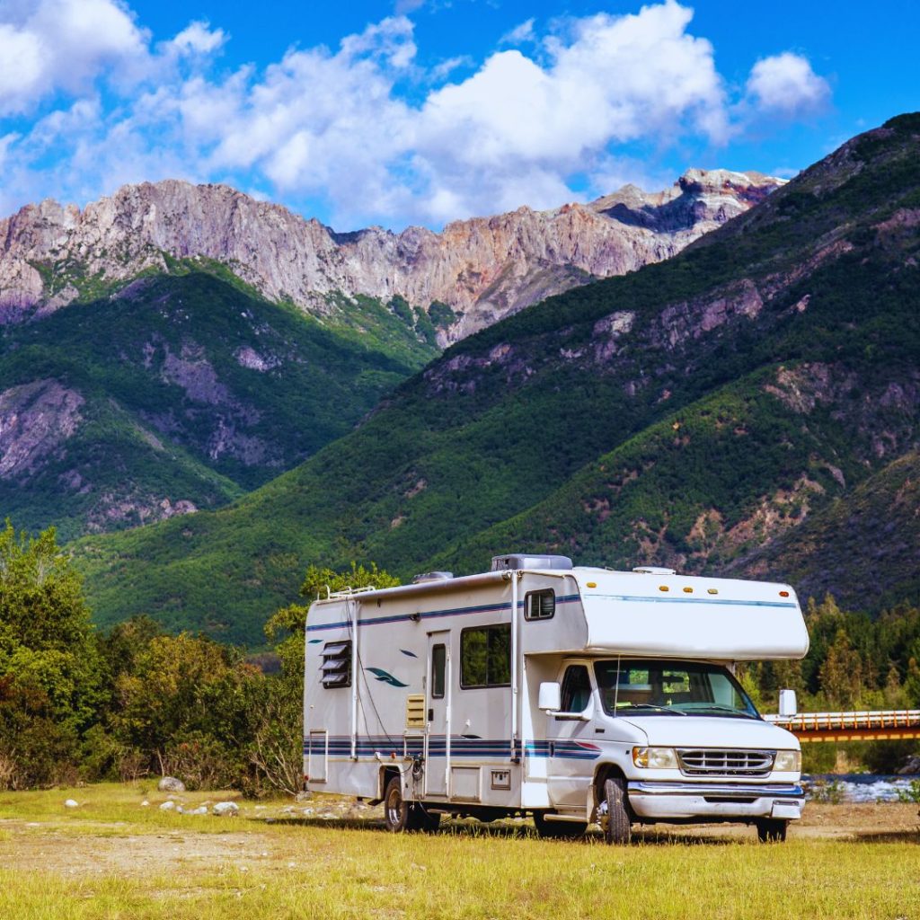 motorhome parked on the grass in front of mountains